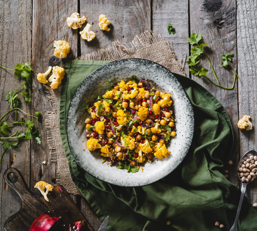 sałatka z patelni żółtym kalafiorem i ciecierzycą. Podana ze świeżą kolendrą i granatem