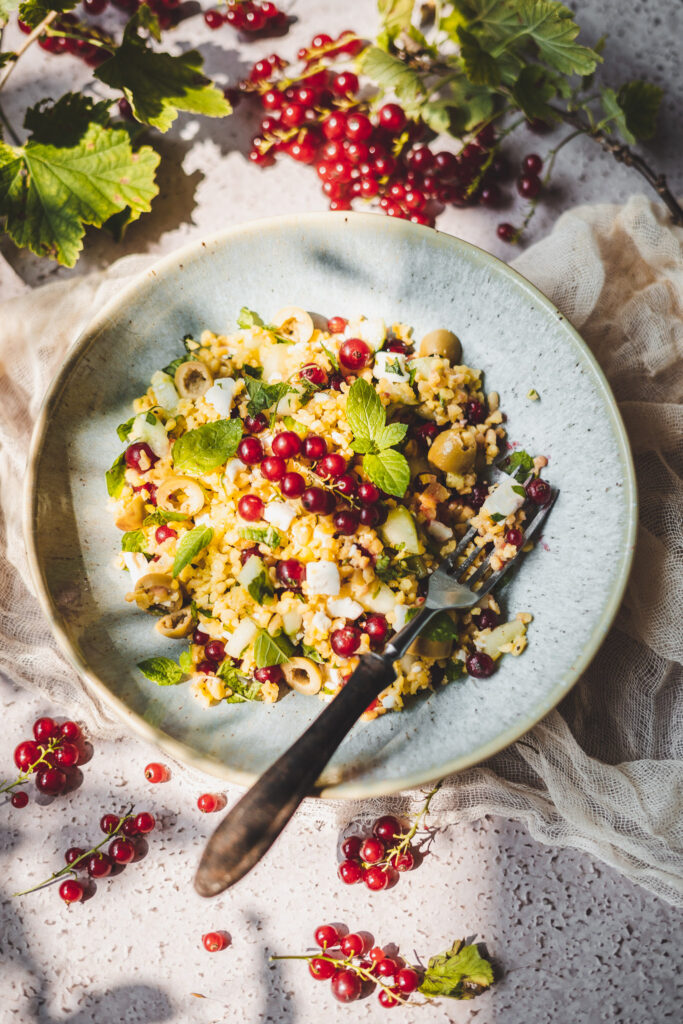 sałatka z bulgurem i czerwoną porzeczką, oliwkami i ogórkiem wyłożona na talerz
